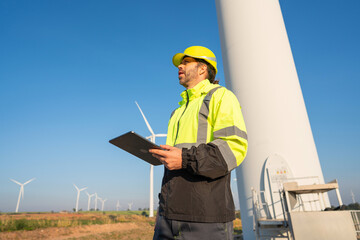 Engineer wearing uniform inspection and survey work in wind turbine farms rotation to generate...