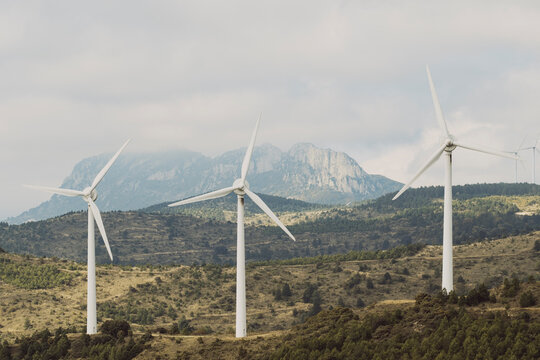 Wind turbines rise over the rural landscape of Navarra, Spain, generating clean, renewable energy. The misty morning enhances the atmospheric scene, symbolizing sustainability and future