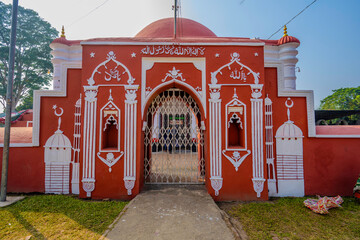 The red-and-white Khan Jahan Ali Majar Jame Mosque in Bagerhat features elegant arches, domes, calligraphy, and a welcoming metal-gated entrance.