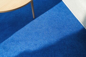 close-up of modern living room setup with bold blue rug beneath minimalist coffee table under soft light
