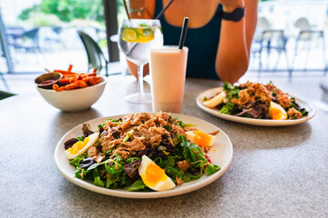 Healthy lunch at the spa: tuna, egg and greens salad, sweet potato fries, a refreshing drink and a smoothie on the table. Relaxation and healthy eating.