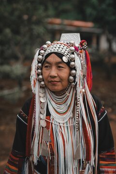 Portrait of an Akha woman in traditional tribal attire with intricate headgear and colorful beads