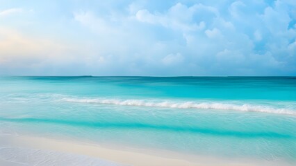 Fototapeta premium Serene turquoise ocean waves gently lapping on a pristine white sand beach under a soft, blue sky.