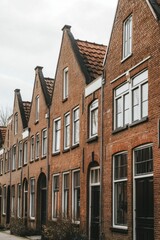 Naklejka premium Historic brick houses line the street in a quaint European neighborhood showcasing traditional architecture and cozy residential life throughout the year