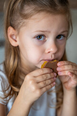 Little girl eating Dubai chocolate with pistachio paste and kataifi dough. Confectionery handmade sweets at home in the kitchen. 