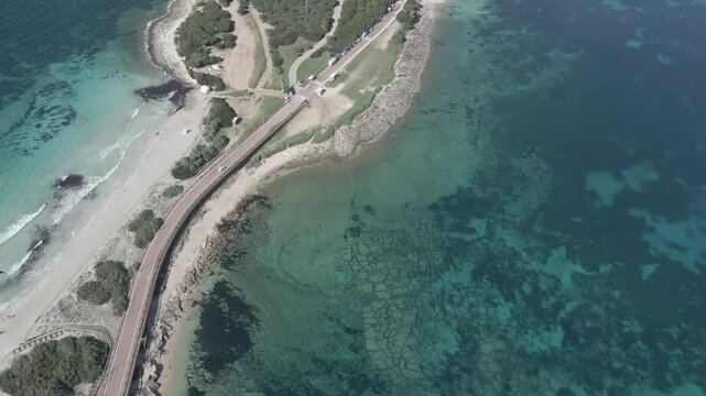 Drone footage of Rena di Levante on Capo Testa, Sardinia, Italy, in summer, featuring white sandy beach, crystal-clear turquoise waters, rolling dunes, and stunning Mediterranean coastline.