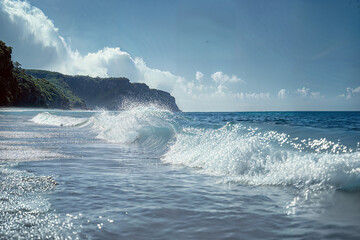 Obraz premium Coastal shoreline with waves under a clear blue sky