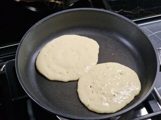 cooking delicious pancakes on a frying pan in the kitchen
