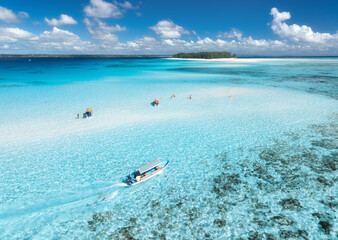 Aerial view of floating boat in transparent azure water on sunny summer day. Mnemba island,...