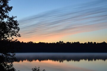 Obraz premium Sunrise Over Lake Gradient: A serene lake with a sky transitioning from pale pink at the horizon to deep blue at the top.