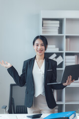 Confident Businesswoman: A  professional woman in a stylish blazer confidently presents her laptop with a warm and welcoming smile.