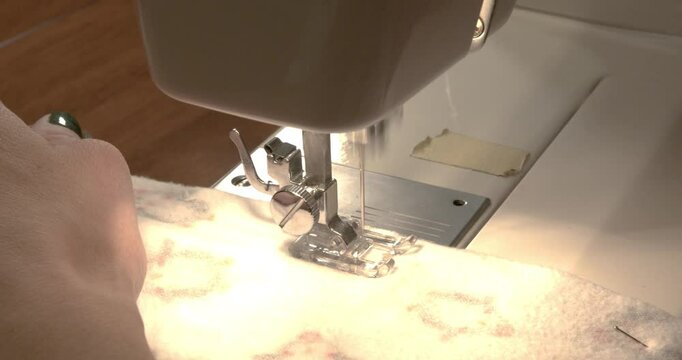 a top down shot of a woman sewing fabric and pulling the pins out as she goes.