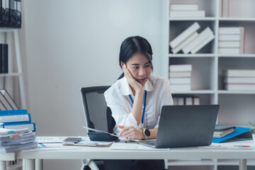 Focused Young Professional Woman at Desk: A young woman sits at her desk, thoughtfully reviewing...