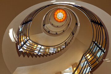 Fototapeta premium Spiral staircase at office building from 1921, view from the basement up