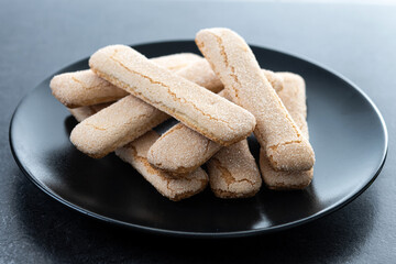 Italian biscuits ladyfingers savoiardi on black slate background