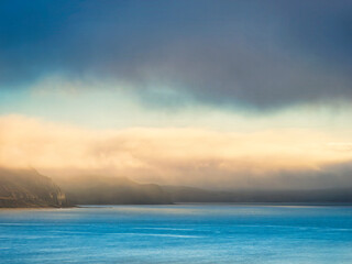 Low hanging mist and vibrant stormy skies over the  jurassic coastline on a winter morning in Dorset England