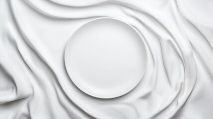 Top view of white empty plate on white silk fabric background for elegant dining presentation