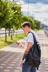 Fototapeta premium Man using a smartphone on a riverside promenade