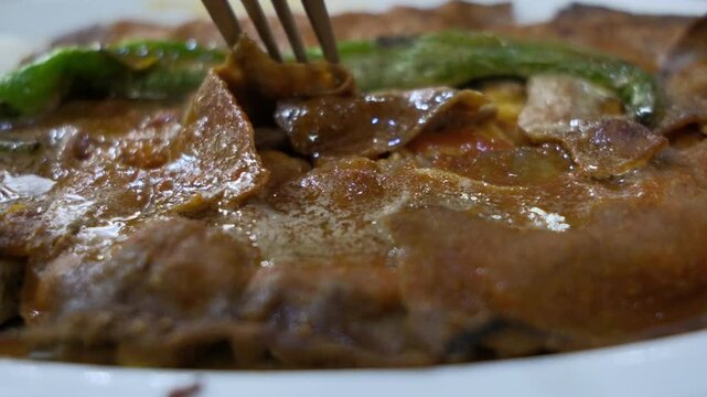 Local Turkish dish Iskender doner on an oval plate in slow motion