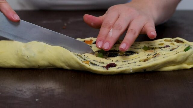 A woman prepares a cruffin with raisins and candied fruits. Rolls the dough cruffin. Tools and ingredients are laid out on the table.