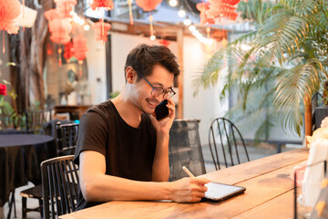 Handsome businessman using tablet to work and talking on mobile phone, don_t smile at coffee shop
