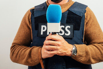 Reporter with bulletproof vest holding a microphone in studio.