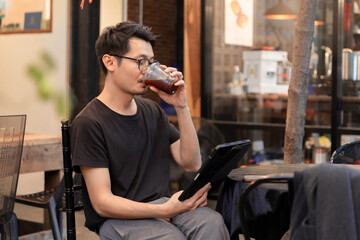 Image of an Asian man working on an iPad and drinking coffee.