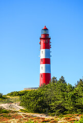 View of the dunes on the North Frisian island of Amrum. Landscape in the north. Nature on the North Sea island with a lighthouse.
