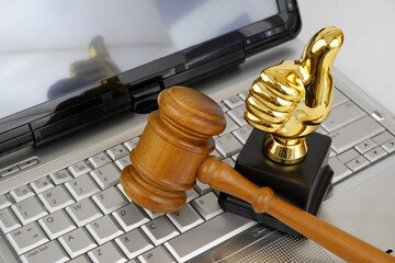 Judge gavel and gold thumbs up on silver laptop computer. Best online legal help concept.