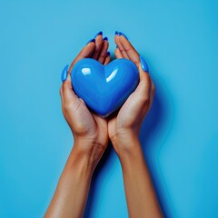 Fototapeta premium Female hands on a blue background holding a blue heart. The concept of donations and family insurance, World Heart Day. valentine's day.