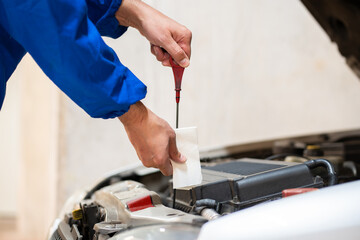 Close up of a studient mechanic checking oil level in a mechanical at school.Grey car