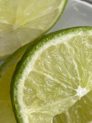 Lime slices, close-up. Green citrus fruit cut into slices. Cooking, cocktail ingredient. Bright juicy background for culinary blogs, drink recipes. Vertical format