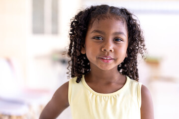 Fototapeta premium African American girl outdoors close-up child pretty smiling looking at camera ethnic schoolgirl standing in park portrait cute small baby pupil kid daughter face in city headshot custody.
