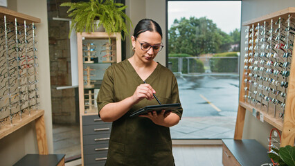 Optometrist Business Owner Reviewing Digital Records in Modern Eyewear Store