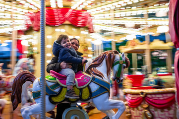 Baby child with his mother riding a horse on a carousel, Italy