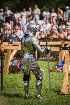 Knight Tournament Participant in Heavy Metal Armor Standing on Grass Field