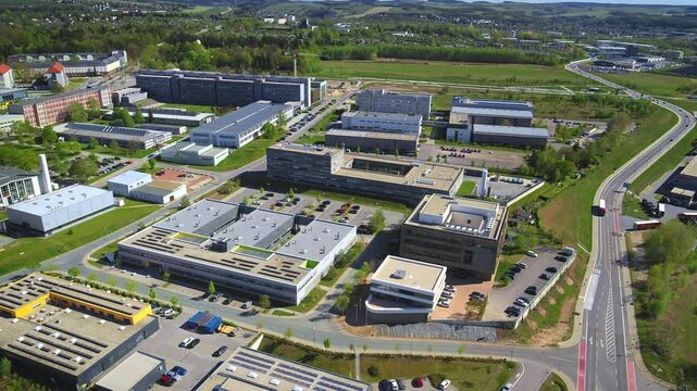 Aerial shot of the Fraunhofer Institute in Chemnitz with sunny weather. Cars drive along the street in the foreground, showcasing the modern architecture of the building. Drone move right