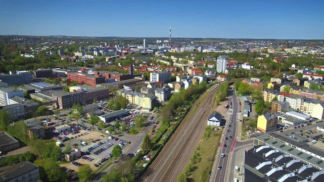 Drone footage of Chemnitz showcasing historic factory buildings, residential areas, and a railway line. In the background, the colorful tower of Chemnitz power plant stands out. Drone move forward.
