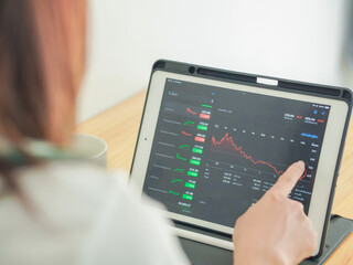 Businessman looking at stock chart on laptop screen. Asian businesswoman working on stocks and investment at home. Close-up of screen showing up and down market and economy chart. Working from home.