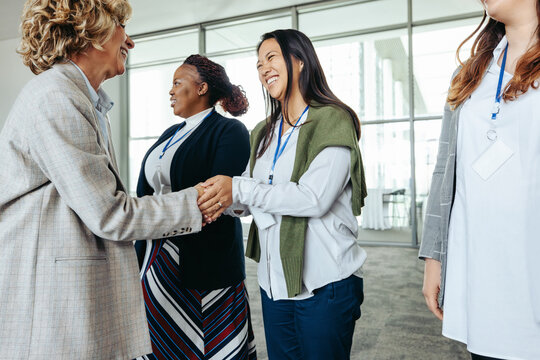 Female business professionals meeting and shaking hands at a corporate event