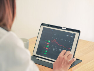 Businessman looking at stock chart on laptop screen. Asian businesswoman working on stocks and investment at home. Close-up of screen showing up and down market and economy chart. Working from home.