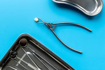 Dental teeth crowns and steel instruments for dental prosthetics, top view. Dentist desk
