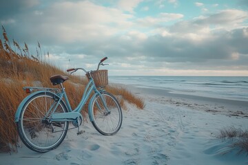Obraz premium Light blue bicycle on sandy beach near ocean. Perfect for travel, vacation, or coastal themes.