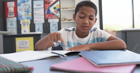 In school, young biracial male student resting head on arms, copy space - Powered by Adobe