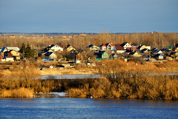 Spring rural landscape - small countryside houses among forest trees in early spring at sunset, birds eye view