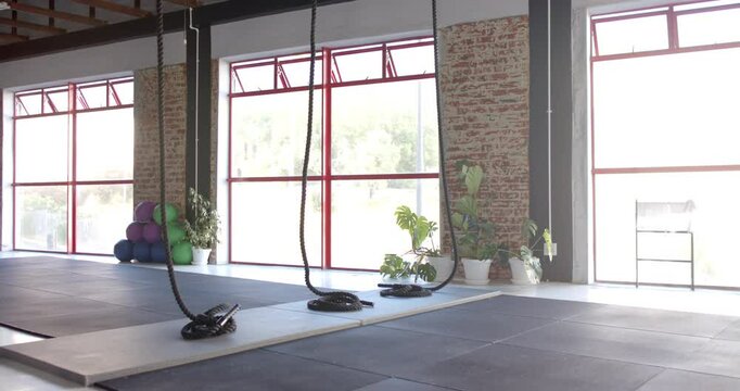 Large windows let sunlight into spacious gym with ropes and mats