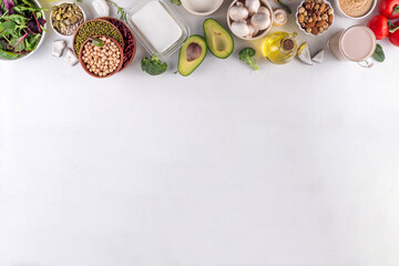 Plant based keto food background with low carb vegan keto diet ingredients, healthy vegetarian fat and protein source. Assortment green vegetables, nuts, legumes, oil, coconut, nuts, peanut butter