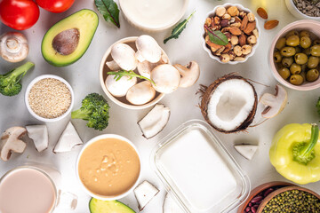 Plant based keto food background with low carb vegan keto diet ingredients, healthy vegetarian fat and protein source. Assortment green vegetables, nuts, legumes, oil, coconut, nuts, peanut butter