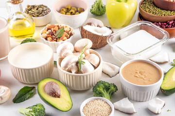 Plant based keto food background with low carb vegan keto diet ingredients, healthy vegetarian fat and protein source. Assortment green vegetables, nuts, legumes, oil, coconut, nuts, peanut butter
