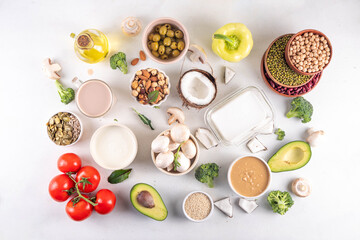 Plant based keto food background with low carb vegan keto diet ingredients, healthy vegetarian fat and protein source. Assortment green vegetables, nuts, legumes, oil, coconut, nuts, peanut butter